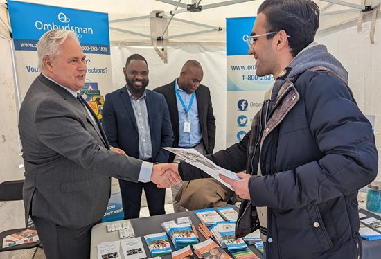 25 mai 2023 : L’Ombudsman Paul Dubé (à gauche) accueille des membres du public en companie d’employés de notre Bureau, à notre kiosque, lors de la Journée des nouveaux arrivants, au Nathan Phillips Square, à Toronto.